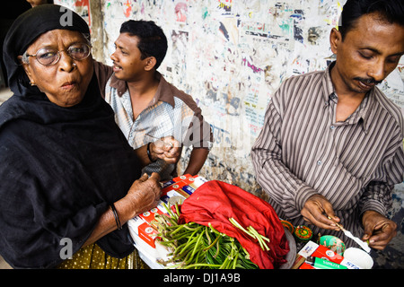 La préparation du vendeur et paan vieille femme la mâcher à la rue de Dhaka, Bangladesh Banque D'Images