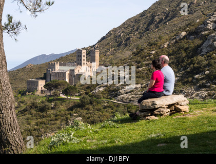 En admirant la vue. Un couple est assis sur un banc en pierre et admire la vue sur les collines et au-delà du monastère de Sant Pere de Rodes. Banque D'Images