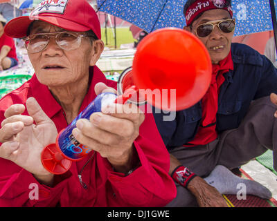 Bangkok, Thaïlande. 19 nov., 2013. Un chandail rouge partisan souffle une corne pour montrer son soutien pour un orateur lors d'un rassemblement à Bangkok. Jusqu'à 30 000 ''Red Shirts'' sont attendus à Bangkok cette semaine à l'avance d'une décision de la cour thaïlandaise qui pouvait provoquer l'effondrement du gouvernement de Yingluck Shinawatra, le premier ministre. Les chemises rouges sont réunis dans un stade de banlieue avant de marcher à la cour. Les chemises rouges sont pour la plupart des agriculteurs et ruraux thaïlandais qui appuient le gouvernement Shinawatra. Crédit : Jack Kurtz/ZUMAPRESS.com/Alamy Live News Banque D'Images