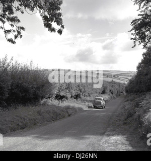 Photo historique d'une scène de l'automobile 1950 l'Angleterre, d'une voiture roulant le long d'un petit chemin de campagne. Banque D'Images