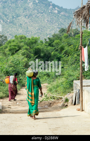 Les femmes indiennes portant un pot en plastique avec de l'eau d'une pompe manuelle dans un village de l'Inde rurale. L'Andhra Pradesh, Inde Banque D'Images