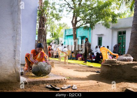 Femme indienne en utilisant une pierre pour moudre des ingrédients pour faire l'extérieur de son chutney maison de village rural. L'Andhra Pradesh, Inde Banque D'Images