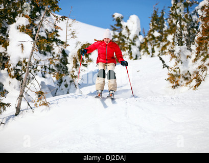 Jeune femme au skieur on snowy slope Banque D'Images