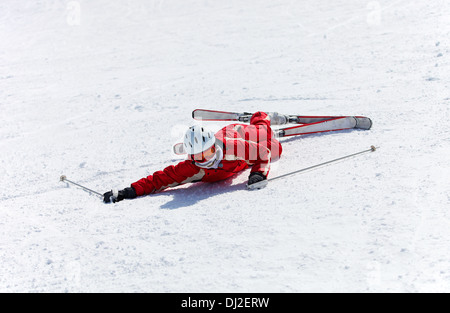 Skieur femelle après tomber sur un versant de montagne Banque D'Images