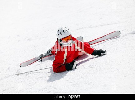 Skieur femelle looking at camera après tomber vers le bas de la pente Banque D'Images