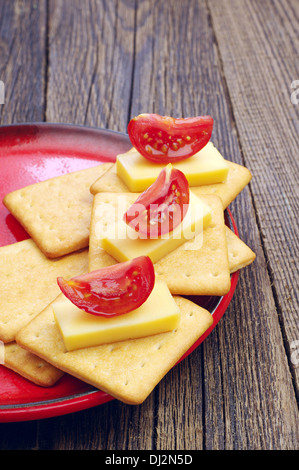 Les craquelins avec du fromage et de la tomate sur la vieille table en bois Banque D'Images