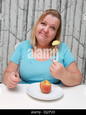 L'excès de femme de manger une pomme sur une assiette. Banque D'Images