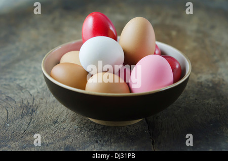 Des oeufs colorés dans un bol sur la table en bois Banque D'Images