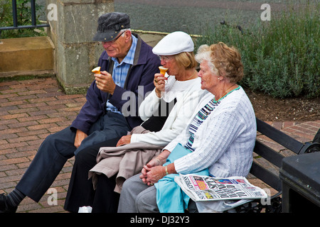 3 Les personnes âgées assis sur un banc la consommation de crème glacée. Telford, Shropshire, West Midlands, England, UK Banque D'Images