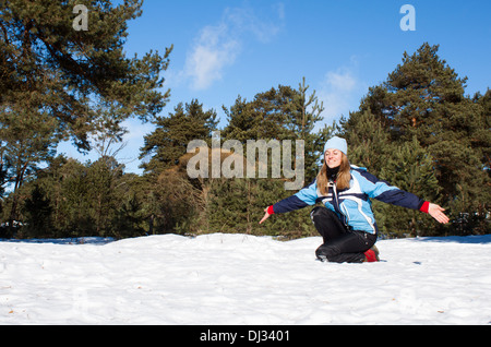 Femme assise blanche neige pinède journée ensoleillée 'les yeux fermés' smiling 'winter scene' Banque D'Images