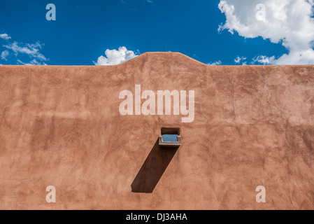 Un mur d'adobe traditionnelles avec canale pour le drainage de la pluie contre le ciel bleu à Santa Fe, Nouveau Mexique, USA. Banque D'Images