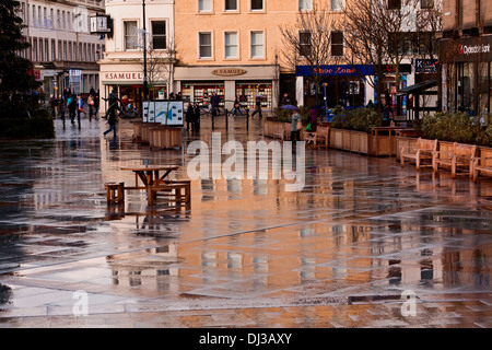 Réflexions colorées de bâtiments montrant sur le trottoirs du centre-ville au cours d'une douche de pluie à Dundee, Royaume-Uni Banque D'Images