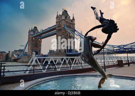 Le Tower Bridge et la statue d'une jeune fille jouant avec dauphin en St Katharine Docks de Londres. Banque D'Images