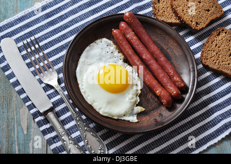 Œuf frit avec les saucisses sur plaque sur fond de bois Banque D'Images