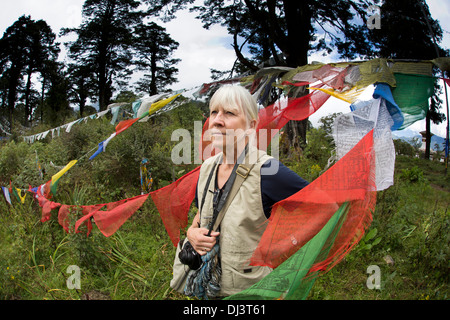 Le Bhoutan, Dochu La pass, haute altitude, middle aged woman parmi les drapeaux de prières colorés Banque D'Images