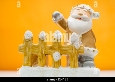 Old Time jaune Santa Claus figurine debout derrière jardin clôture et brandissant d'une main Banque D'Images