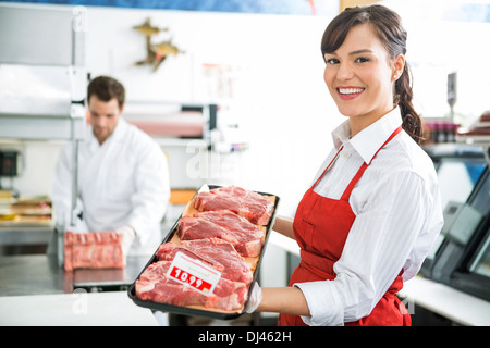 Heureux Butcher Holding Bac viande en magasin Banque D'Images