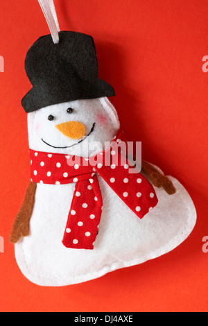 Le Snowman wearing foulard rouge à pois noir et top hat decoration prêt pour Noël sur fond rouge Banque D'Images