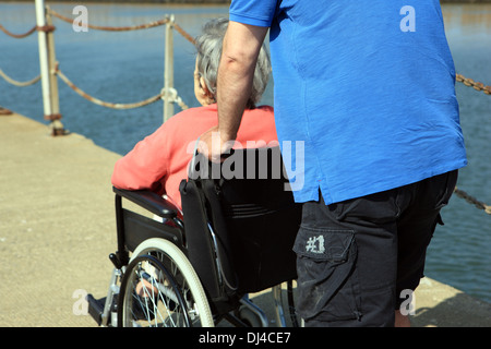 Homme poussant une vieille dame dans un fauteuil roulant Banque D'Images