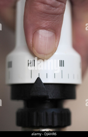 La main de l'homme le réglage d'une vanne thermostatique sur un radiateur à la maison. Banque D'Images