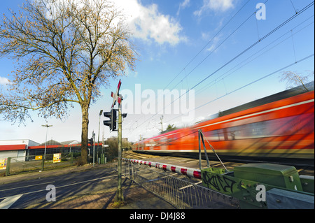 Un train de voyageurs passant un passage à niveau Banque D'Images