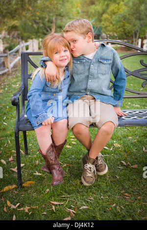 Heureux les jeunes frère et Sœur, assis sur un banc à l'extérieur. Banque D'Images