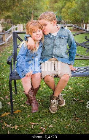 Heureux les jeunes frère et Sœur, assis sur un banc à l'extérieur. Banque D'Images