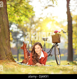 Jeune femme se détendre sur une herbe verte à vélo dans un parc sur une journée ensoleillée Banque D'Images