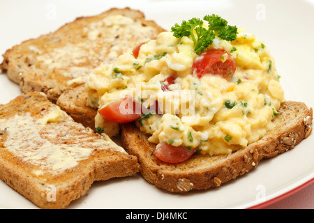 Des œufs brouillés sur les toasts avec du persil et des tomates cerises, Banque D'Images