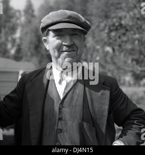 Photo historique, 1950s. Portrait d'un fier petit porteur ou d'un petit fermier dans les vêtements de l'époque et d'une casquette plate, debout sur son pays, Norfolk, Angleterre, Royaume-Uni. Banque D'Images