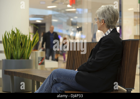 Femme assise sur un banc et regarda un homme Banque D'Images