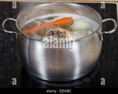 Mijoter le bouillon de poulet en pot d'acier sur une plaque de cuisson close up Banque D'Images
