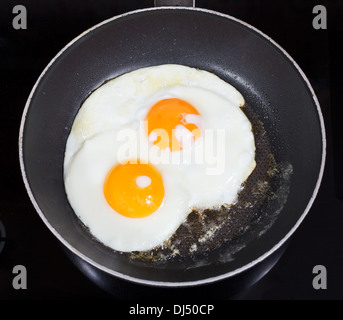 Vue de dessus de deux œufs frits dans une poêle sur une cuisinière électrique Banque D'Images