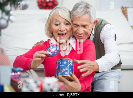 Surpris Senior Woman with Man Looking at Christmas Gift Banque D'Images