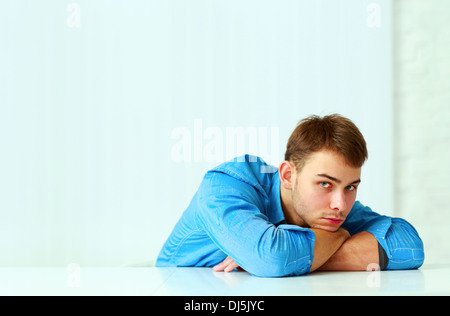 Les jeunes pensive businessman portant sur la table et regardant la caméra Banque D'Images