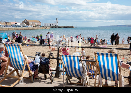 Personnes touristes visiteurs assis dans des transats South Beach front de mer en été Scarborough North Yorkshire Angleterre Royaume-Uni Grande-Bretagne Banque D'Images