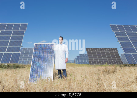 Scientist holding solar panel in rural landscape Banque D'Images