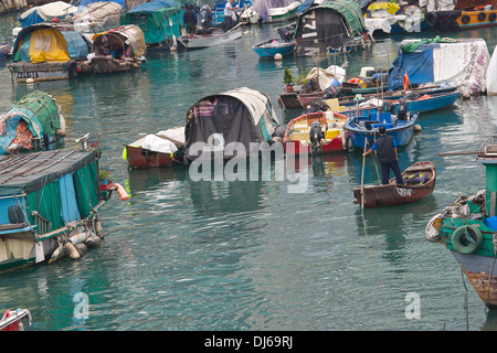 L'homme chinois passé rangées dans un typhon Sampans amarrés au logement, Hong Kong. Banque D'Images