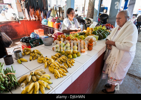 En attente de service sur le marché. Une vieille femme attend pour son fruit pour être préparé au marché de Ticul. Banque D'Images