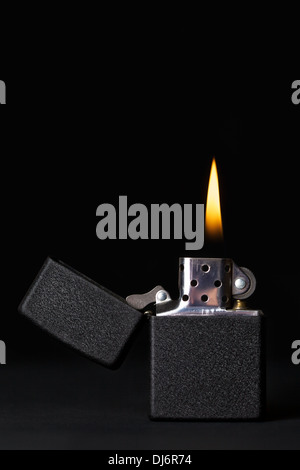 Briquet à essence noir avec flamme sur fond sombre Banque D'Images