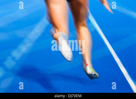 Les jambes de coureuse floue sur bleu race track Banque D'Images