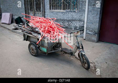 Petit vélo avec panier rempli de morceaux de plastique et de ferrailles dans un hutong, Beijing, Chine Banque D'Images