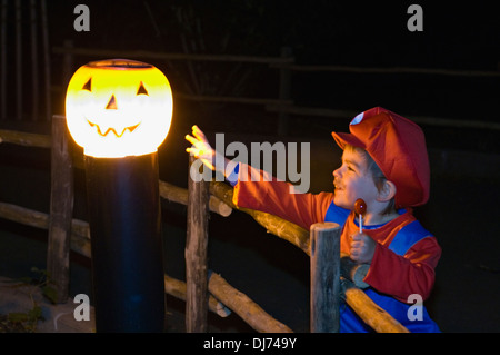 Enfant déguisé en Mario atteint vers jack-O-lanterne sur le sentier à côté de la lampe au Zoo de Louisville Halloween Party Banque D'Images