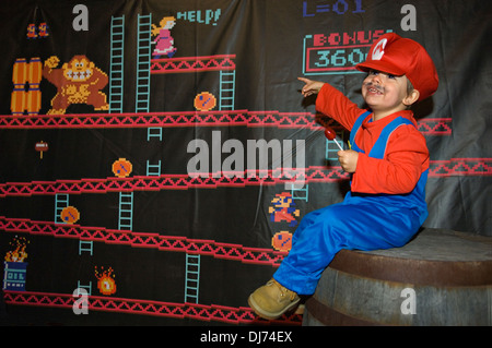 Enfant déguisé en Mario assis sur le fût avec Donkey Kong Banner derrière au Zoo de Louisville Halloween Party à Louisville Banque D'Images