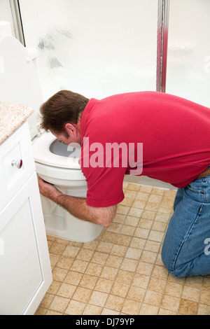 L'homme à genoux dans la salle de bains, vomissements dans les toilettes. Banque D'Images