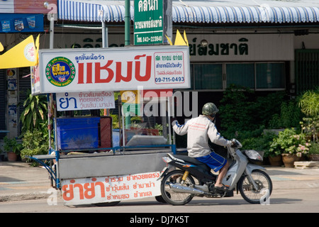 Un vendeur est l'extraction d'un panier alimentaire de motocyclette sur une rue de la ville de Khon Kaen, Thaïlande. Banque D'Images