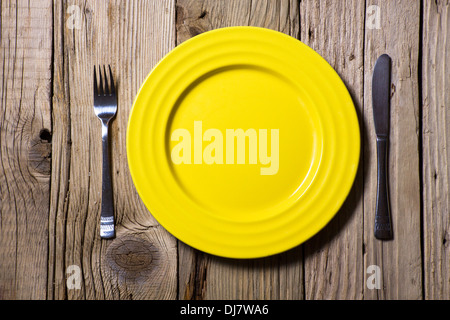 Des couverts et de la plaque jaune sur table en bois rustique Banque D'Images