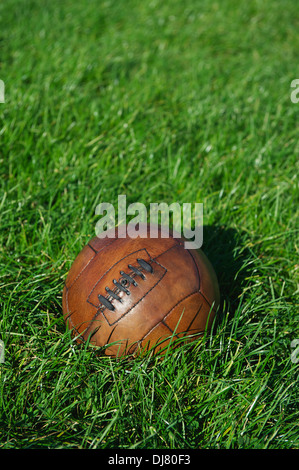 Vintage brown football soccer ball se trouve à sunny Green grass field Banque D'Images