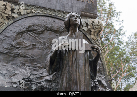 Statue d'une femme qui prie et tenant une croix au Cimetière Bellu, Bucarest, Roumanie Banque D'Images