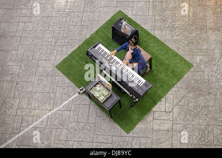 Enfant jouant du piano électrique. Vue aérienne d'une jeune fille jouant au piano électrique dans un centre commercial. Banque D'Images